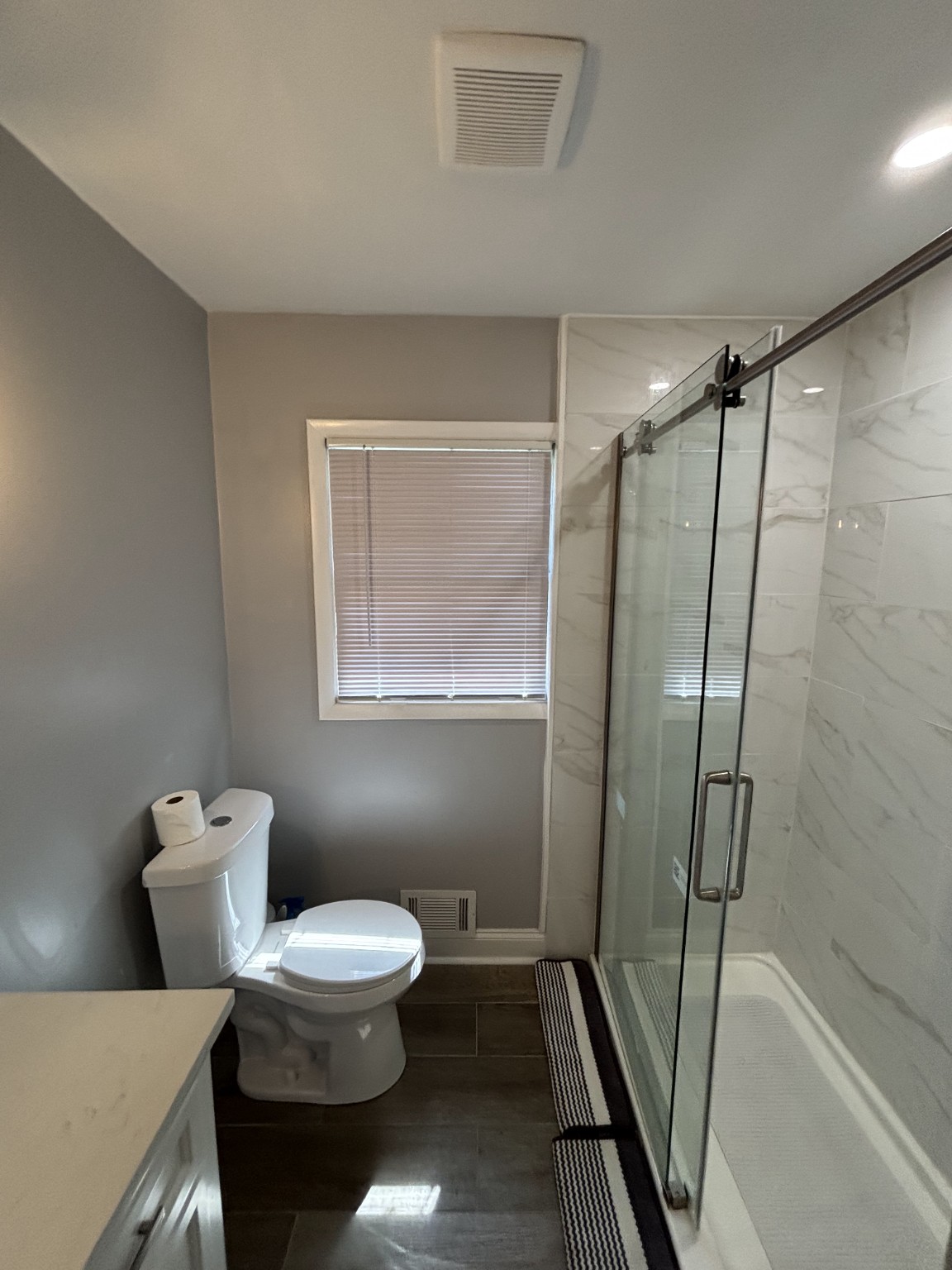Finished bathroom with gray walls, a glass shower enclosure, and updated flooring
