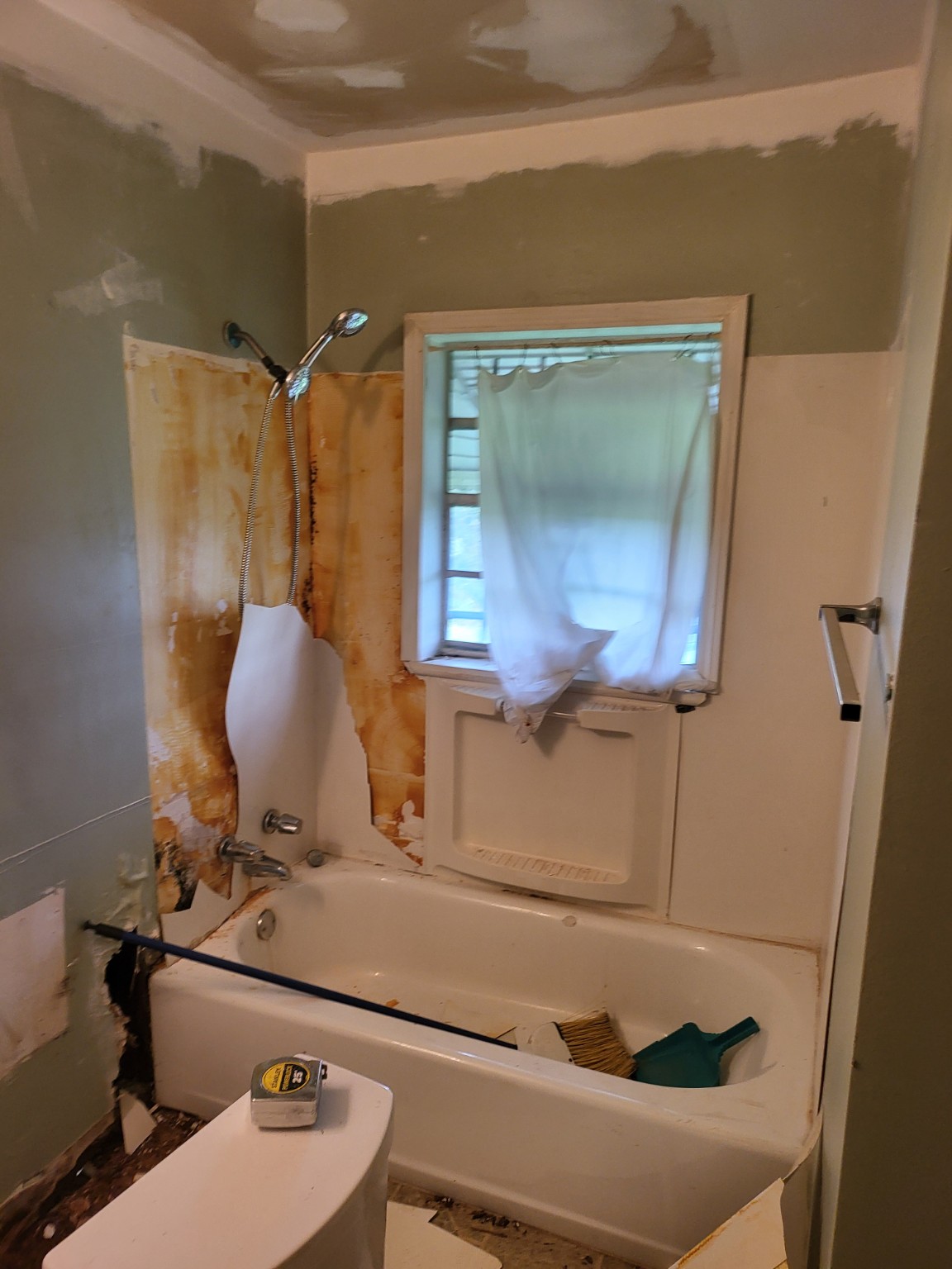 Bathroom during renovation with the original tub and shower wall exposed