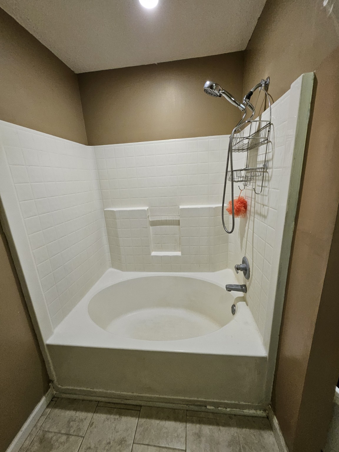 Bathroom before renovation with an inset white tub and white tile surround