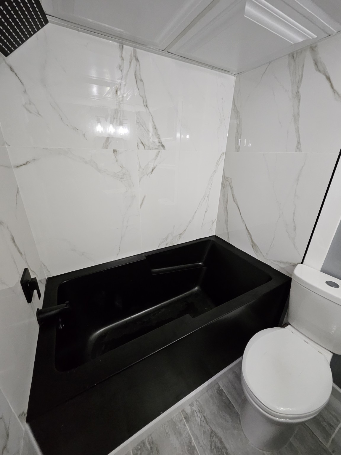Renovated bathroom with a black tub and marble-look tile