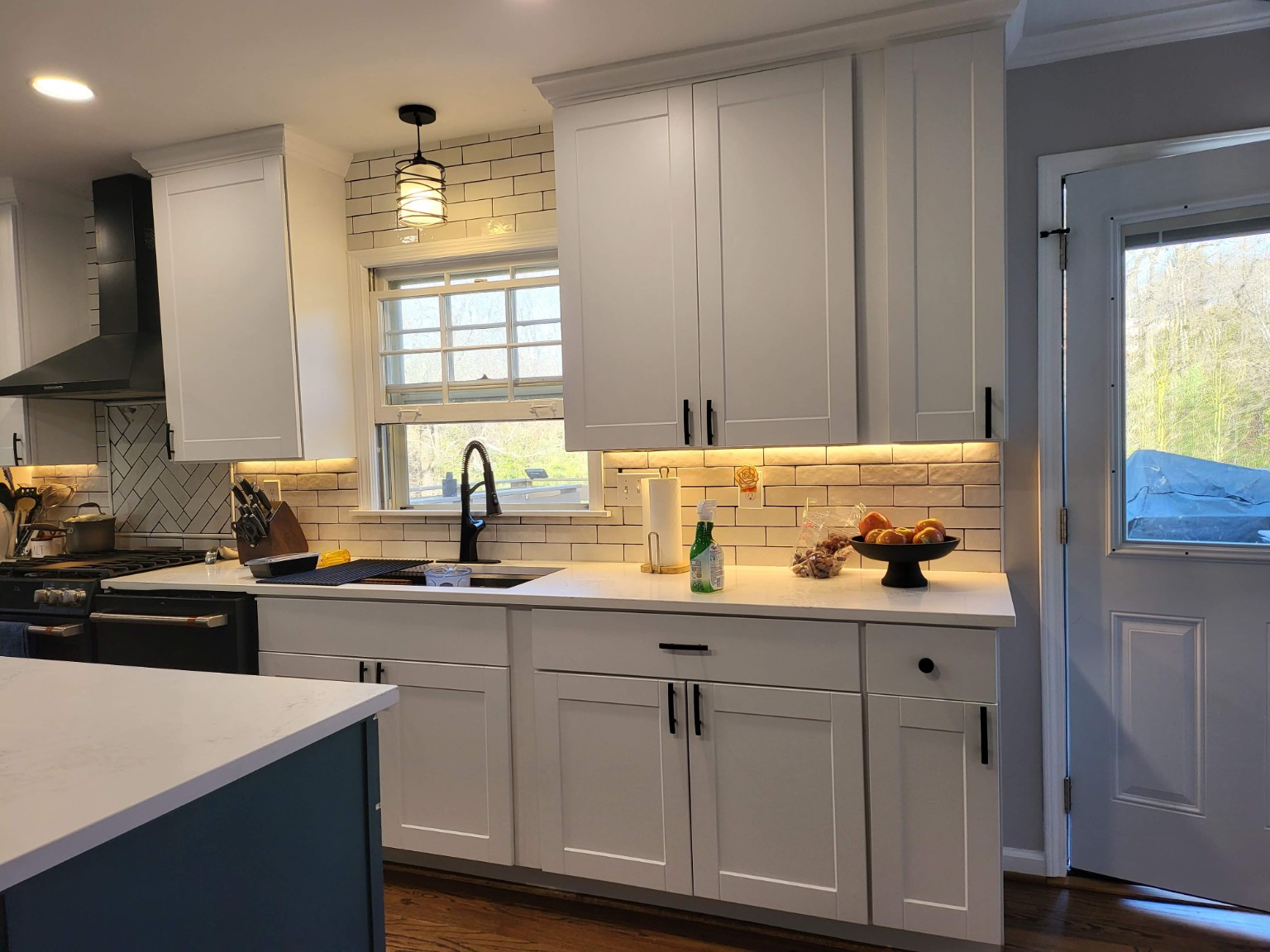 Finished kitchen with white cabinetry, tile backsplash, and black faucet