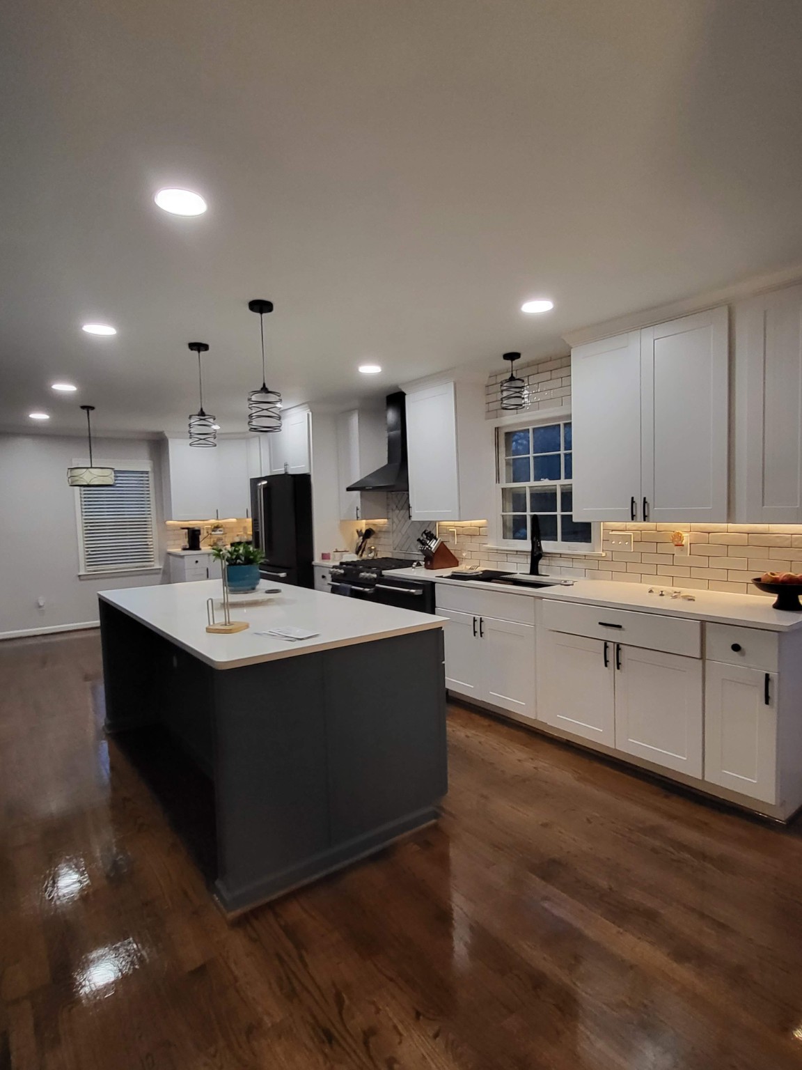 Finished kitchen with blue island, white cabinets, and hardwood floors