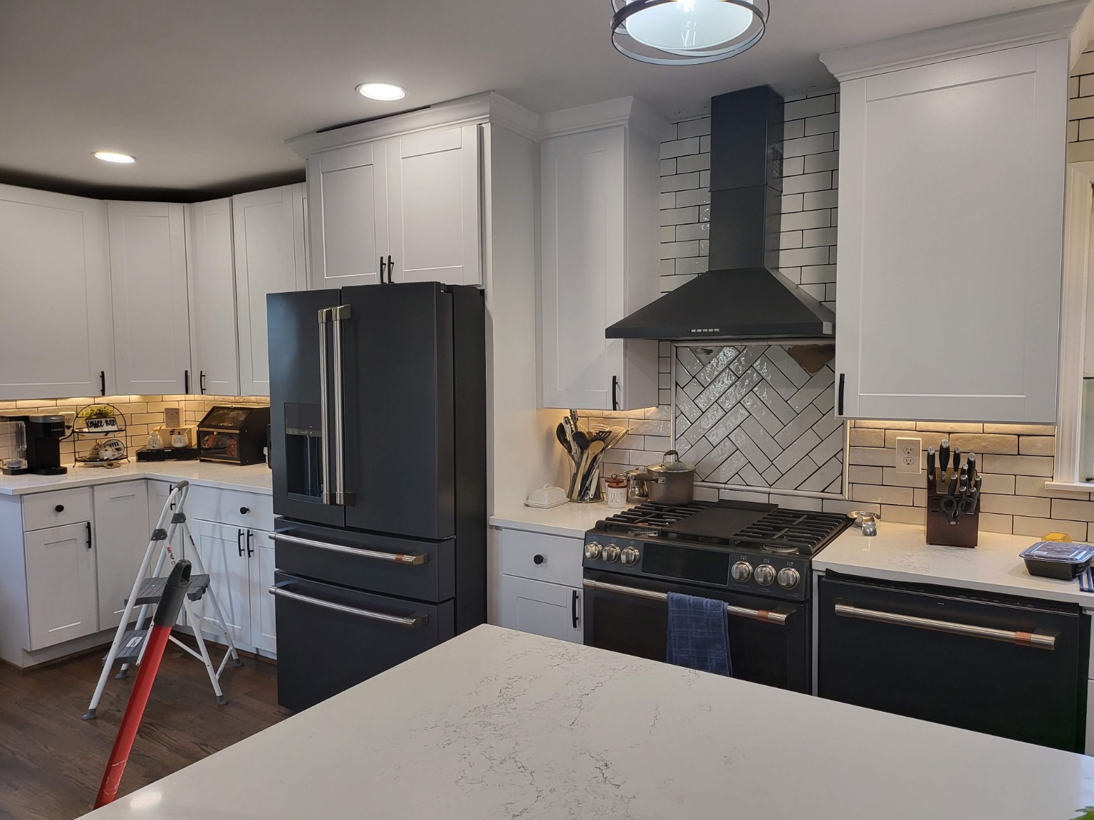 Finished kitchen range, hood, and white tile backsplash