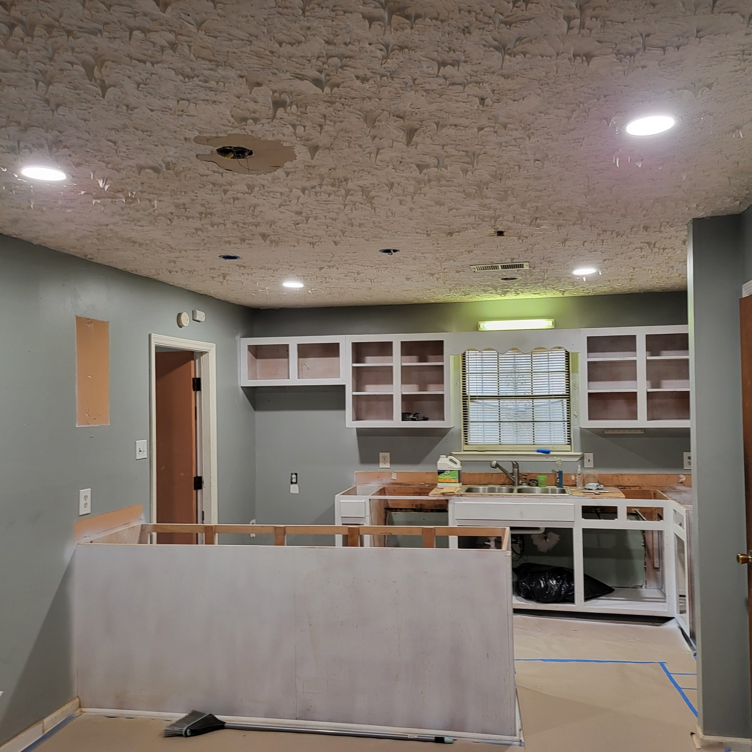 Kitchen during renovation with open cabinets and island under construction