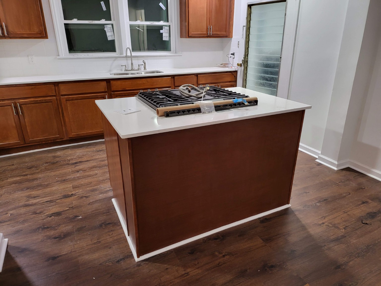 Wood cabinet kitchen with white island countertop and range awaiting installation
