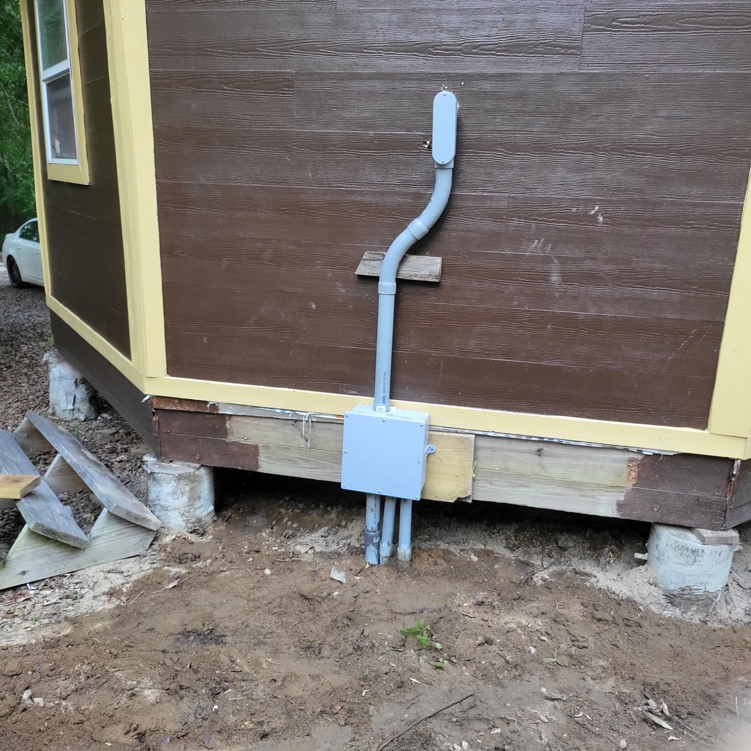 Exterior electrical junction box and conduits at the base of a building